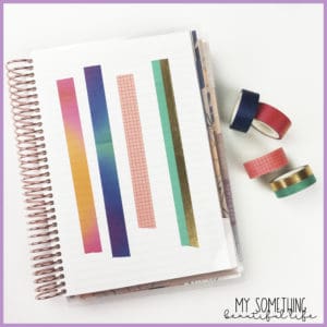 open notebook with washi tape samples on page. 4 rolls of washi tape are next to the notebook